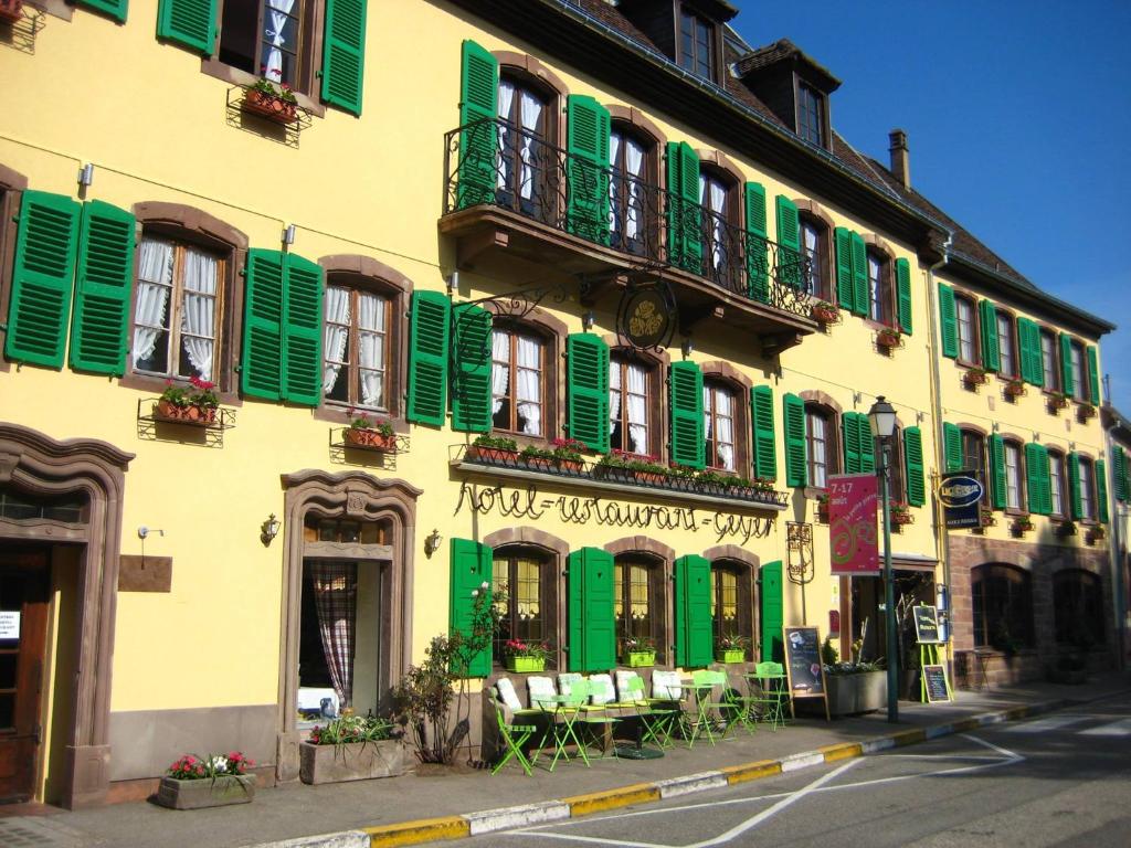 a yellow and green building with green shutters at Hotel Restaurant Aux Trois Roses in La Petite-Pierre