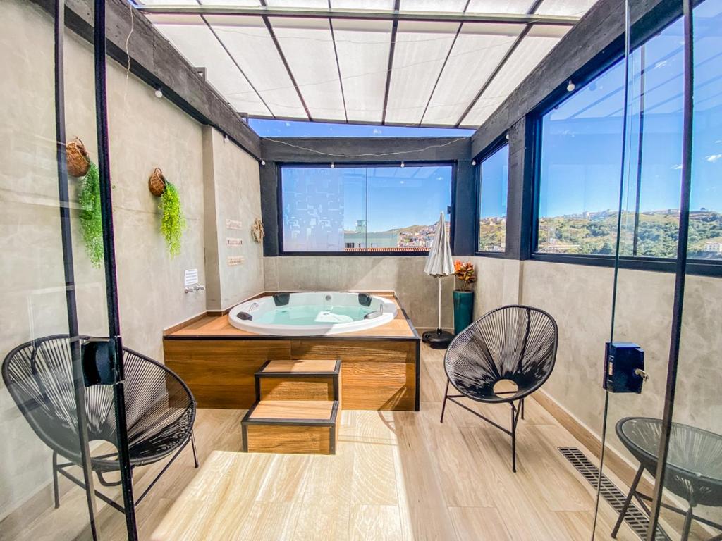 ein großes Bad mit einer Badewanne und 2 Stühlen in der Unterkunft Uai House com jacuzzi (Espaço romântico) in Poços de Caldas