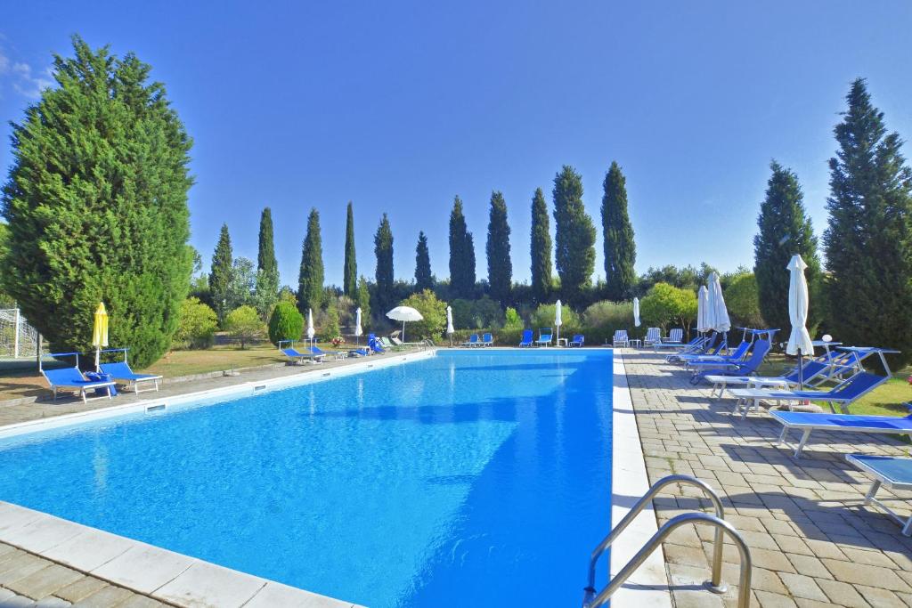 a large swimming pool with blue lounge chairs and trees at Casa Guna in Asciano