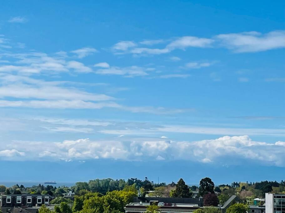 a blue sky with clouds and buildings and trees at Luxury downtown 2 bedroom suite with Ocean views in Victoria