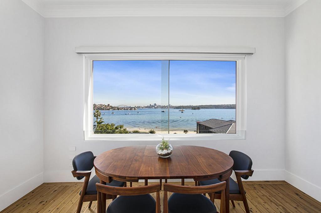 Un comedor con una mesa y un gran ventanal. en Harbour View in Rose Bay, en Sídney
