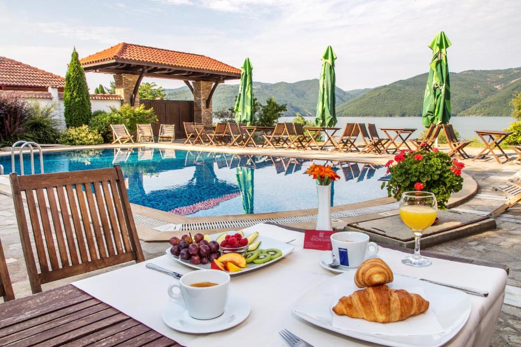 a table with breakfast food and drinks next to a swimming pool at Family Hotel Saint Konstantin in Glavatartsi