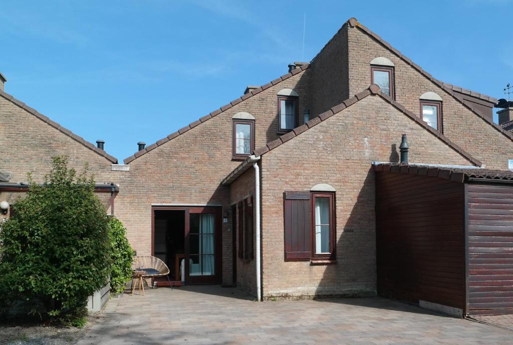 uma casa de tijolos com uma garagem em frente em Strandgeluk, Joost de Moorstraat 6 em Cadzand