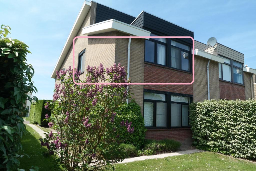 Una casa con una flecha rosa en el costado. en Dolfijn, Wijk de Brabander 92 en Cadzand