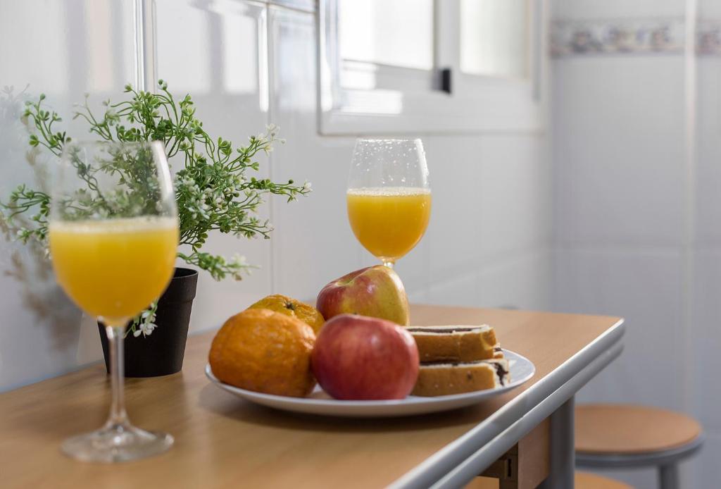 a plate of fruit and two glasses of orange juice at Brisas Estadio Playa Victoria in Cádiz