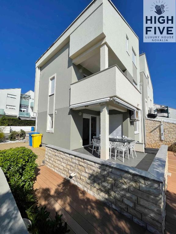 a white house with a patio and a table at Apartment High Five Novalja in Novalja