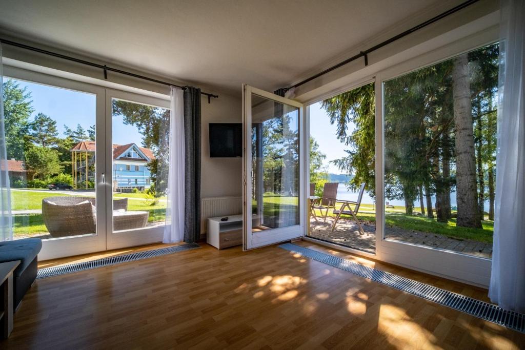 una sala de estar vacía con ventanas grandes y vistas en Apartment Riviera 503-1 Lipno Home, en Lipno nad Vltavou