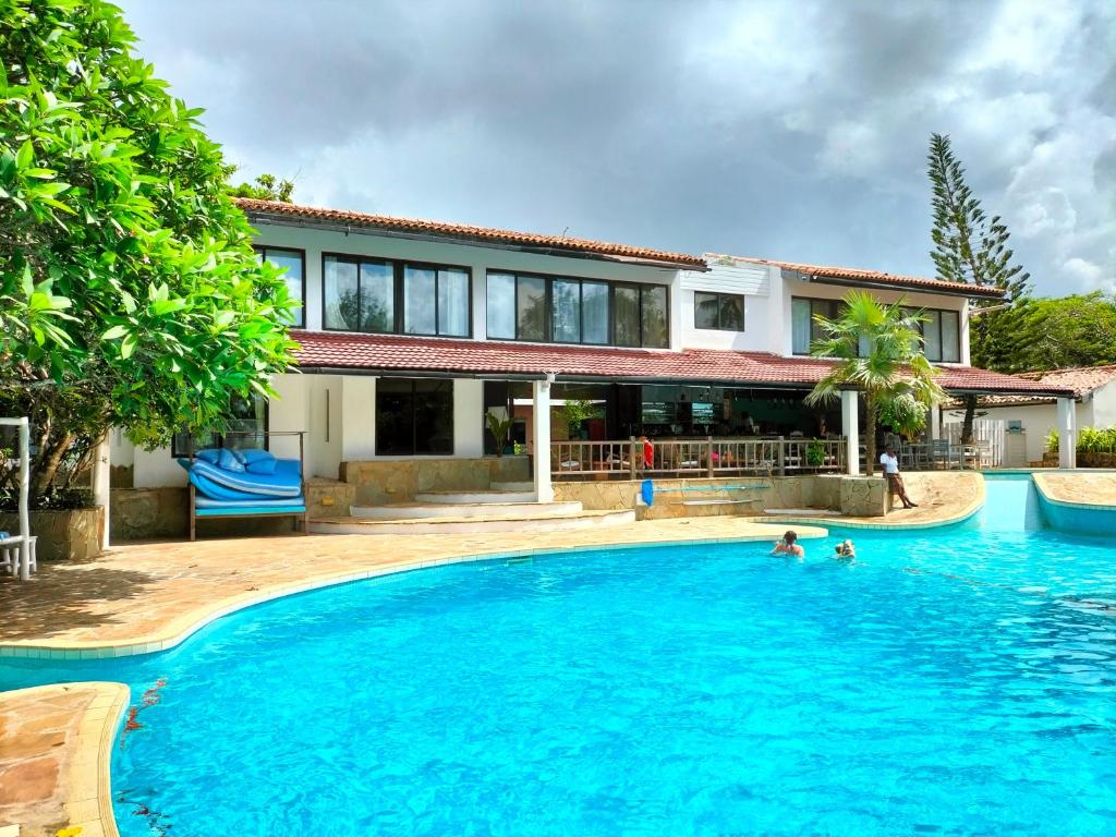 a house with a swimming pool with two people in it at Flamboyant Diani Beach in Diani Beach