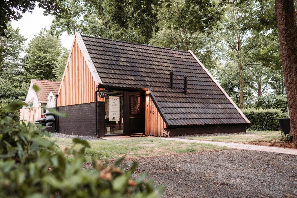 Het Houten Huisje 84 Luxe vakantiewoning Zuid Limburg في سيمبيلفيلد: حظيرة حمراء صغيرة مع سقف أسود