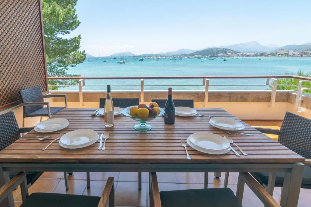 a wooden table with a bowl of fruit and a view of the ocean at Ed Bellveure 2 A in Port de Pollensa