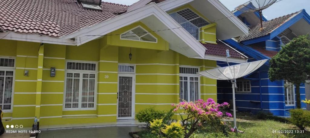 a yellow and blue house with an umbrella at Villa Berastagi Mas in Berastagi