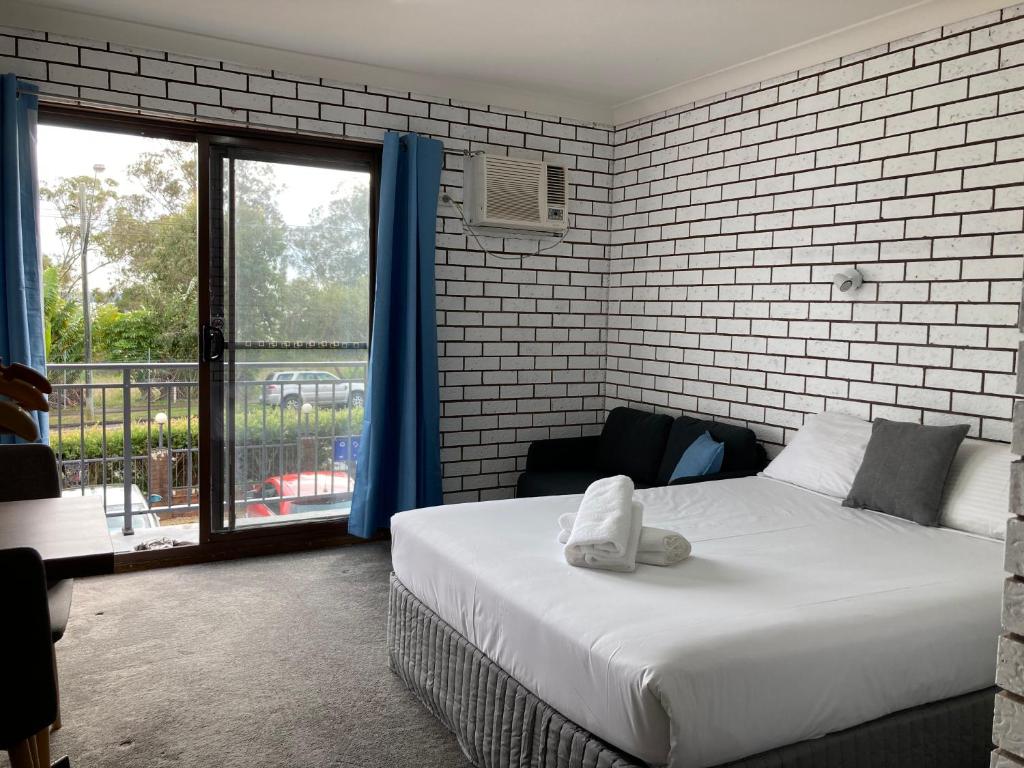 a bedroom with a bed and a large window at Toukley Motel in Toukley