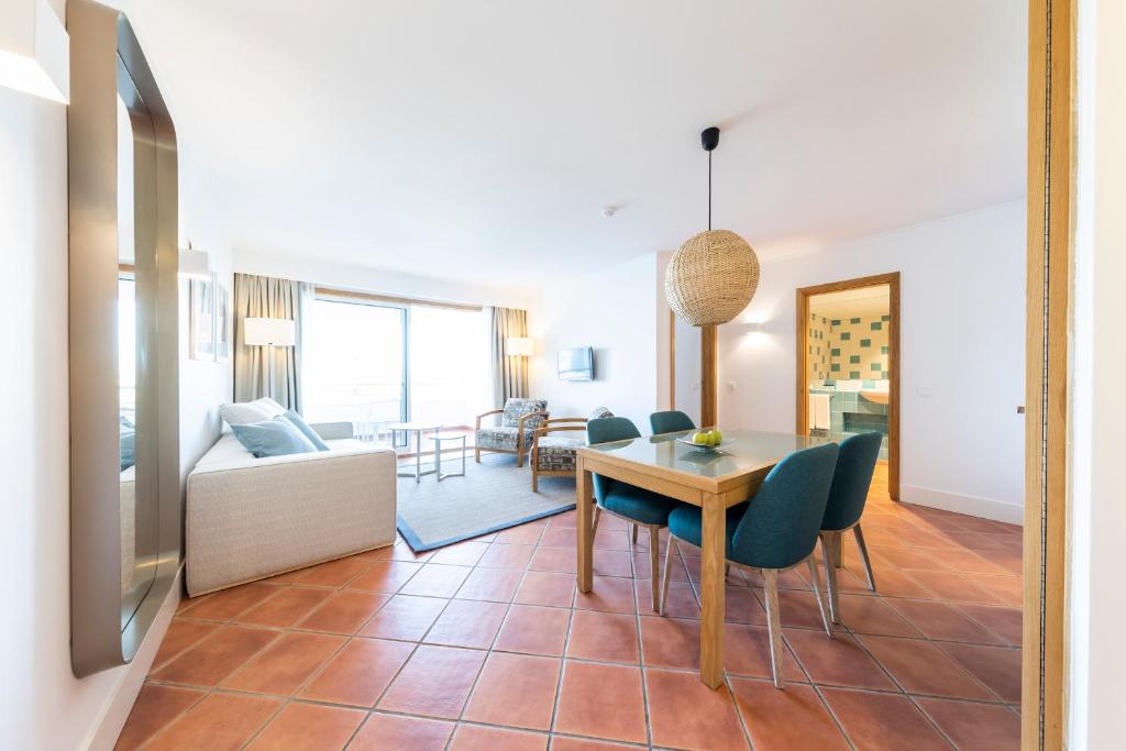 a dining room and living room with a table and chairs at The Patio Suite Hotel in Albufeira