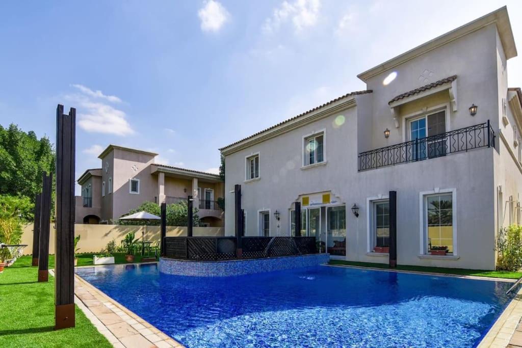 a villa with a swimming pool in front of a house at Frank Porter - Arabian Ranches in Dubai
