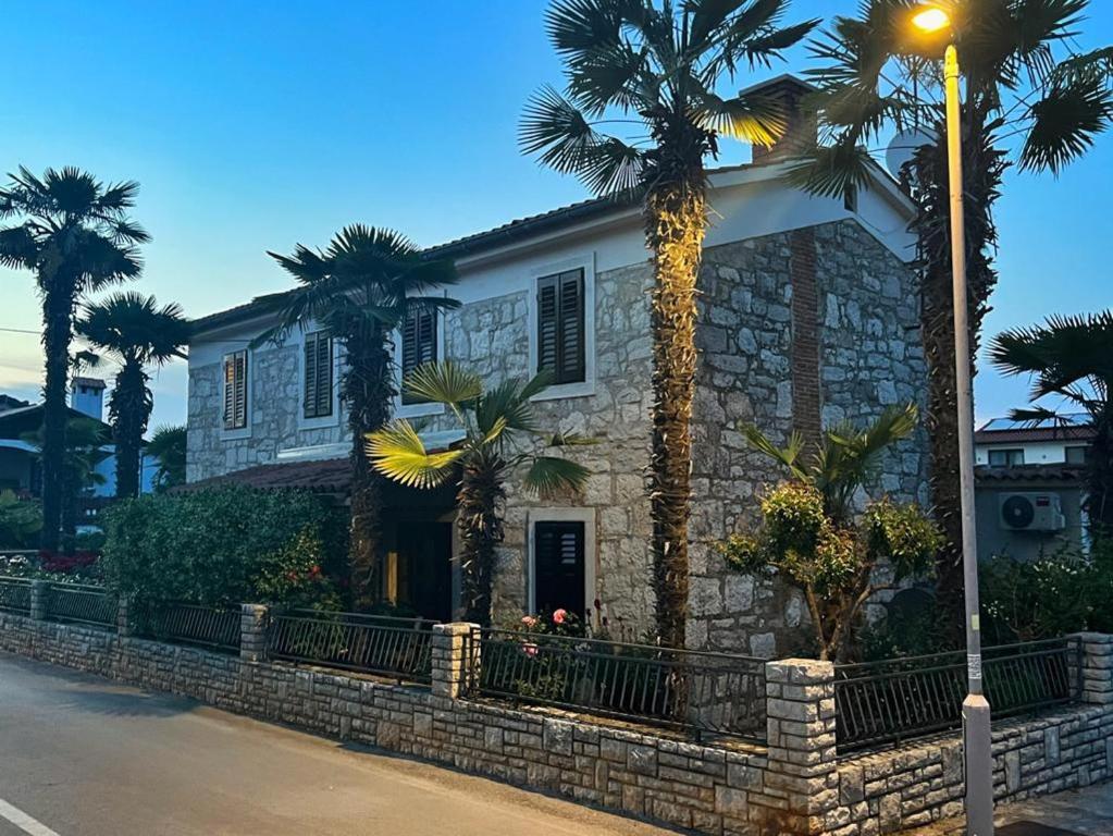 a stone house with palm trees and a street light at Apartments Karmen Funtana in Funtana