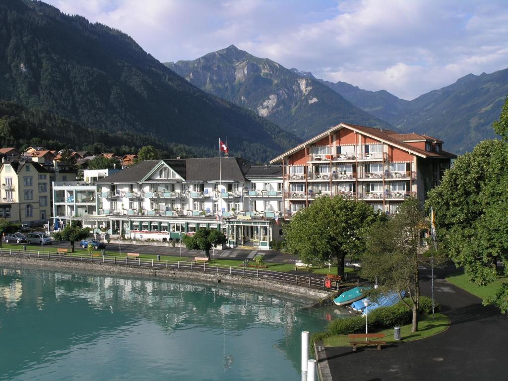 un hôtel et une rivière avec des montagnes en arrière-plan dans l'établissement Seiler au Lac, à Bönigen
