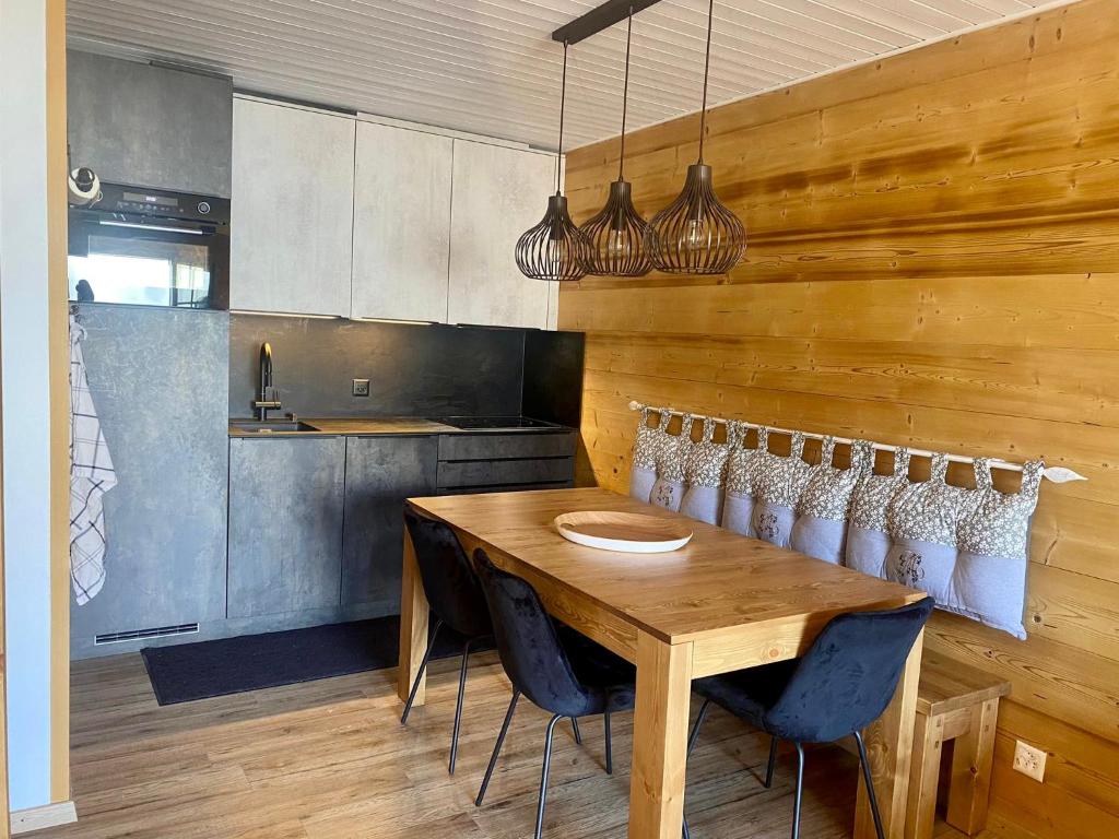 een eetkamer met een houten tafel en stoelen bij Appartement tout confort in Champoussin