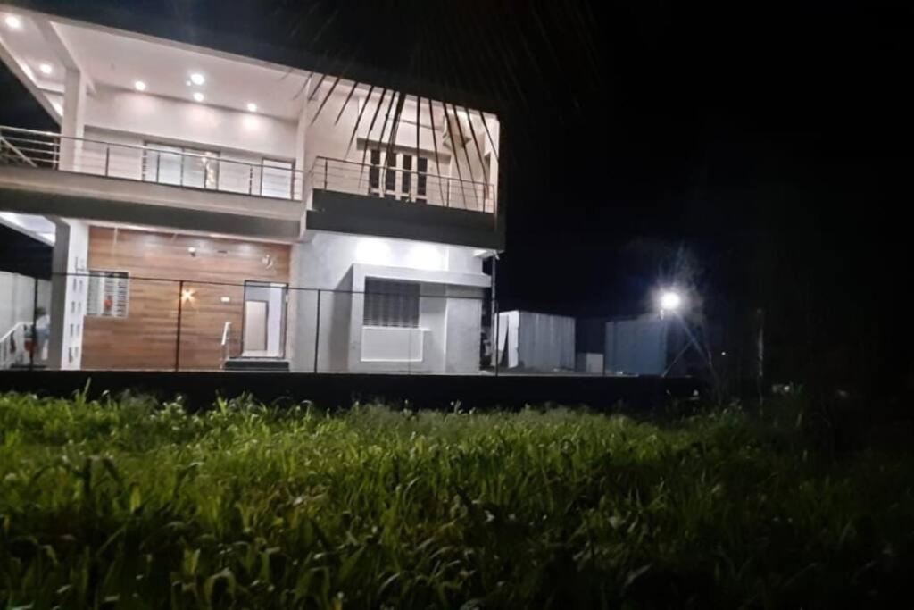 ein Haus in der Nacht mit Rasen davor in der Unterkunft Nisarg Farm Villa in Shirdi