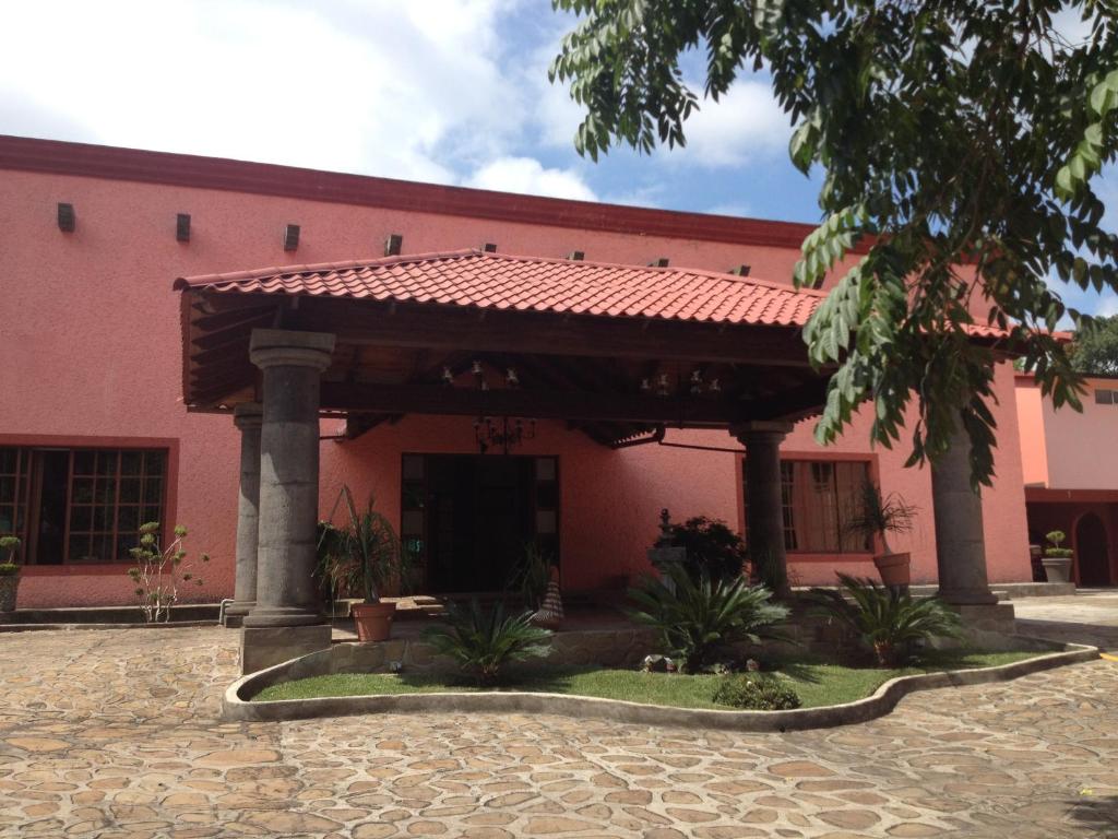 a pink building with a red roof at Hotel Hacienda Prom in Misantla