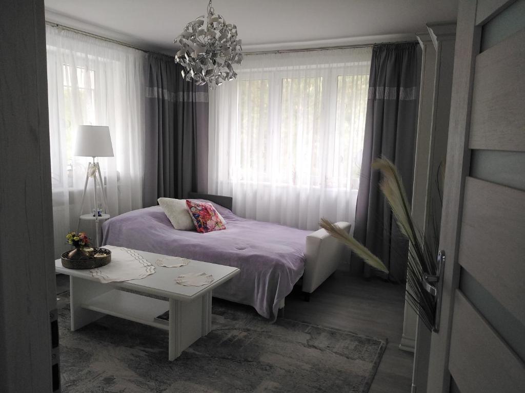 1 dormitorio con cama, mesa y lámpara de araña en Pokoje gościnne Słupy Olsztyn - parking, en Olsztyn