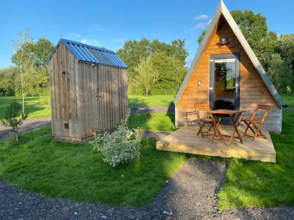 eine kleine Hütte mit einem Tisch und Stühlen im Gras in der Unterkunft Countryside Cabin in Taunton