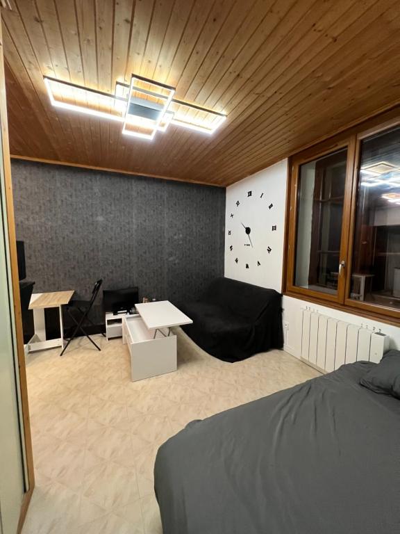 Zimmer mit einem Bett, einem Tisch und einer Uhr in der Unterkunft Magnifique Studio de 20m2 pour 1 à 4 personnes in Les Rousses