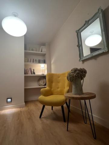 Habitación con silla amarilla y mesa con espejo. en Hostal Crisami en Solsona