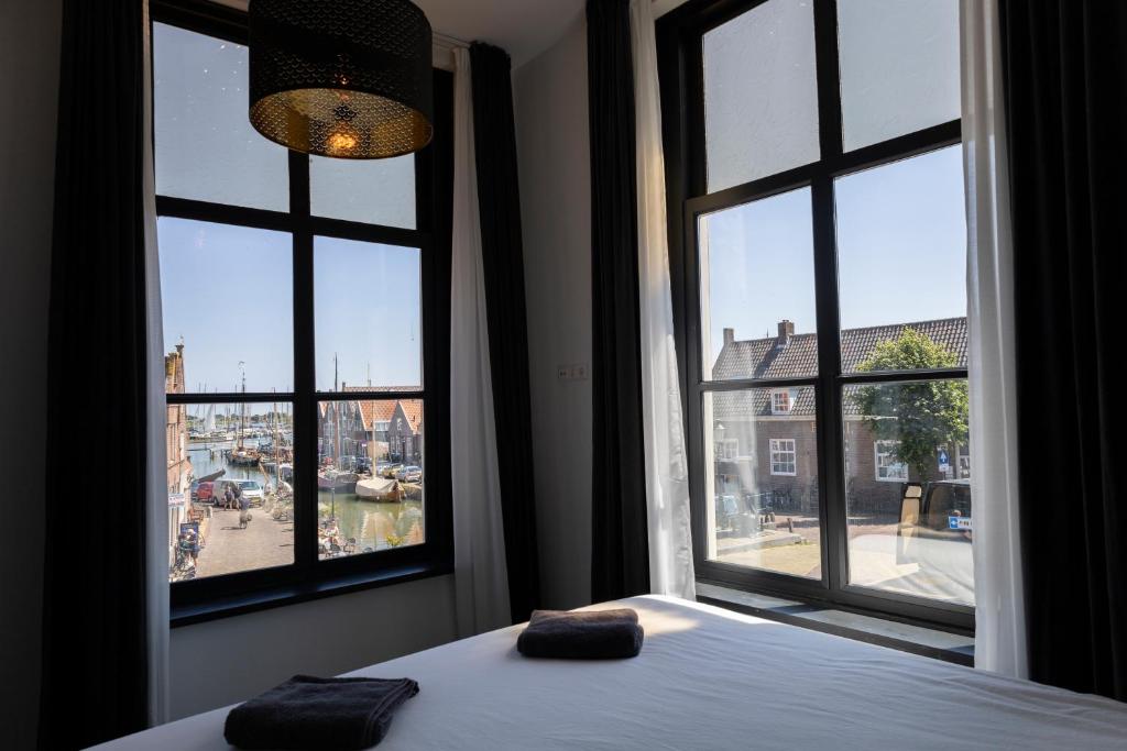 a bedroom with two pillows on a bed and two windows at Hotel Monnickendam in Monnickendam