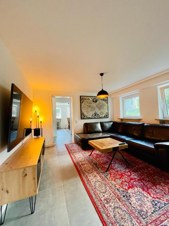 a living room with a black leather couch and a rug at Lichtdurchflutetes Souterrain Apartment in Schapen in Braunschweig