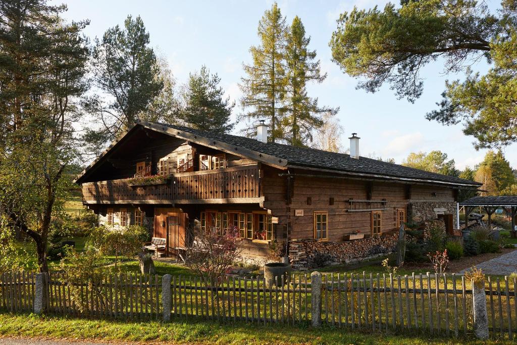 una vieja casa de madera con una valla delante en Volarská roubenka, en Volary