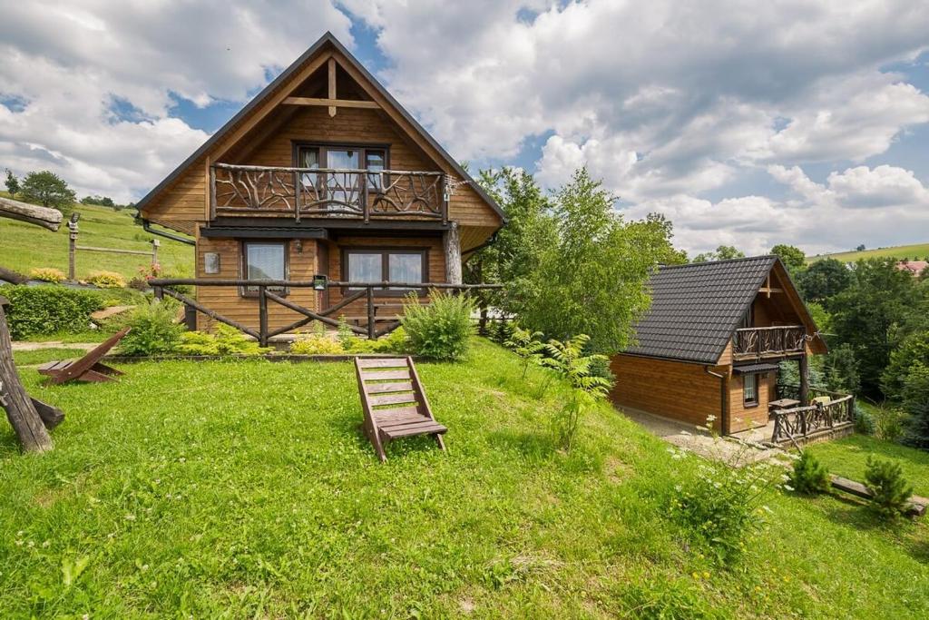 a log cabin with a bench in the grass at Osada Ostoja in Radziejowa