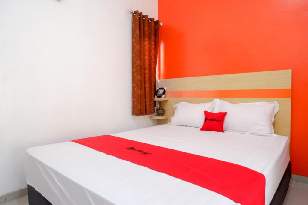 a red and white bed with a red blanket on it at RedDoorz Syariah near Alun Alun Kota Rembang in Rembang