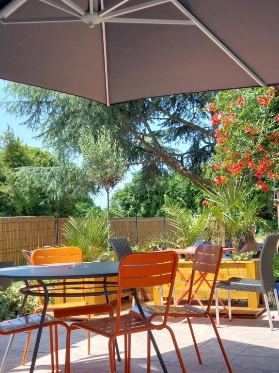 a table and chairs under an umbrella on a patio at Hôtel Amaya in Ambarès-et-Lagrave
