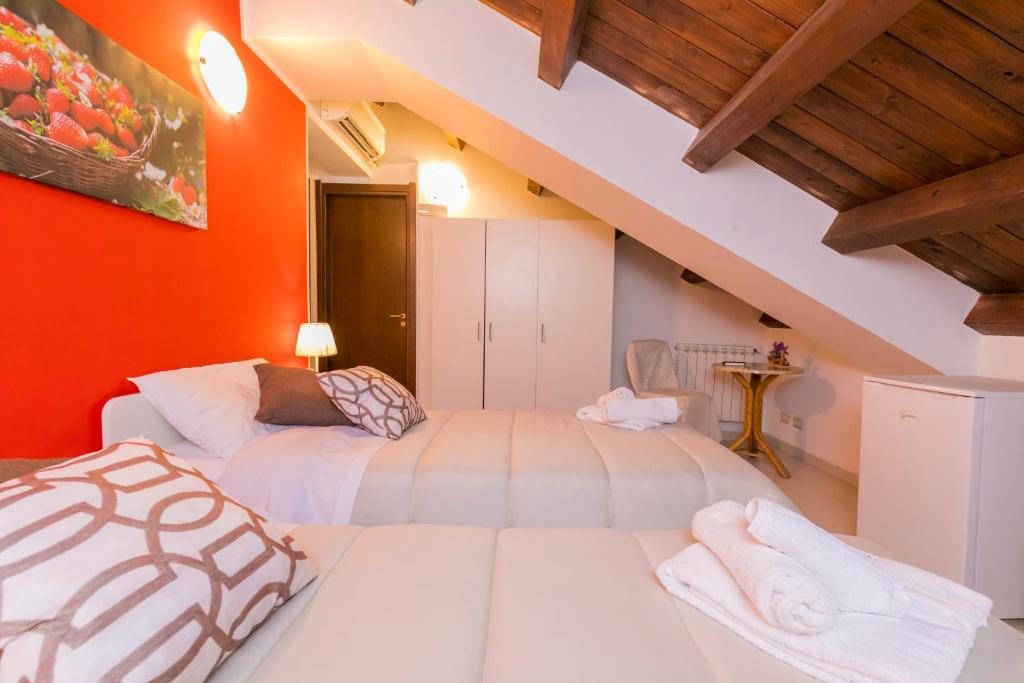2 Betten in einem Zimmer mit orangefarbener Wand in der Unterkunft TERRA MIA in Città Giardino