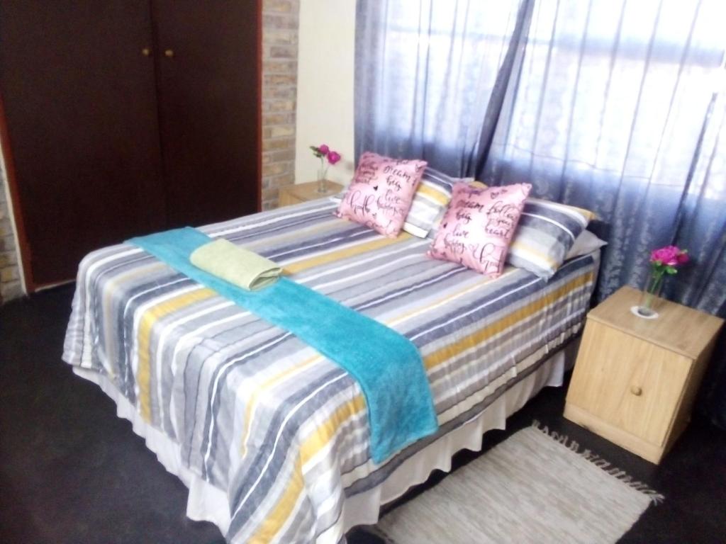 a bed with pink and blue sheets and pillows at KHAYA LANGA Guest House & Contractors Accommodation in Machadodorp