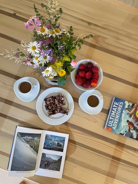 a table with bowls of fruit and flowers and a book at Mountain Heart House in Bosanski Petrovac