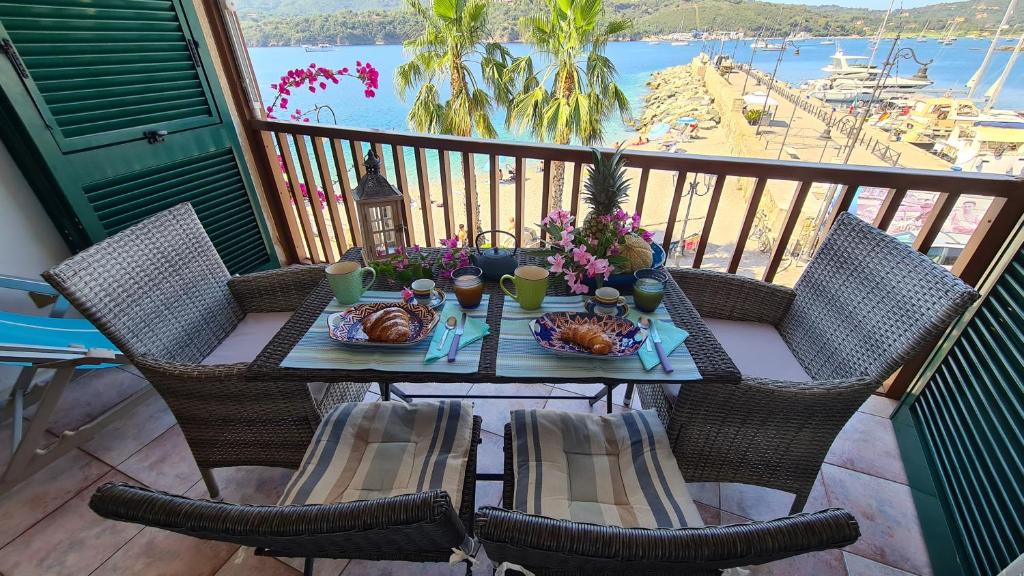 una mesa con comida y flores en el balcón en La Pianotta Sulla Spiaggia, en Porto Azzurro