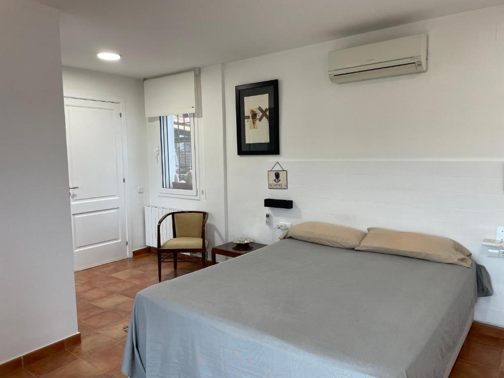 a white bedroom with a bed and a chair at Smallville - Sitges Apartamento independiente para 4 personas con piscina in Sant Pere de Ribes