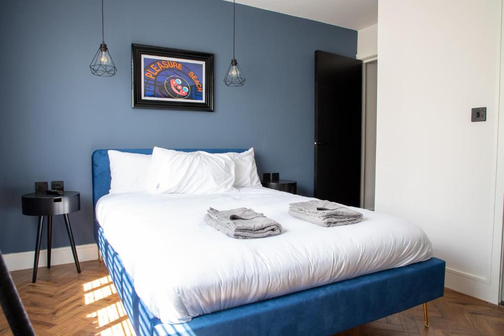 a blue bedroom with a bed with towels on it at Withnell Stays - Apartment Five in Blackpool