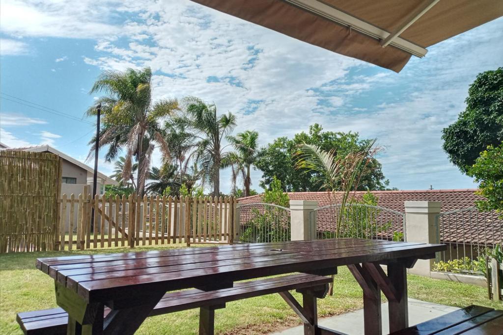 a wooden picnic table in a yard with a fence at Marks Cottages in Durban