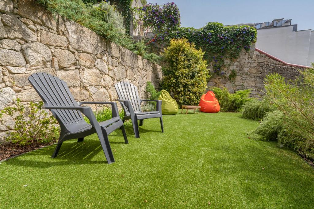 two chairs sitting in the grass next to a stone wall at OPO Downtown Blue in Porto