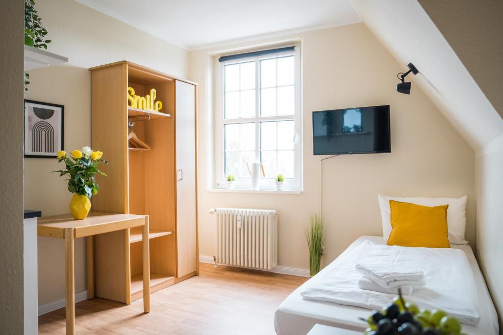 Habitación pequeña con cama y TV. en Alte Feuerwache, en Berlín