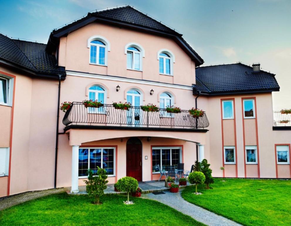 een groot roze huis met een balkon bij Dom na Wzgórzu in Sarbinowo