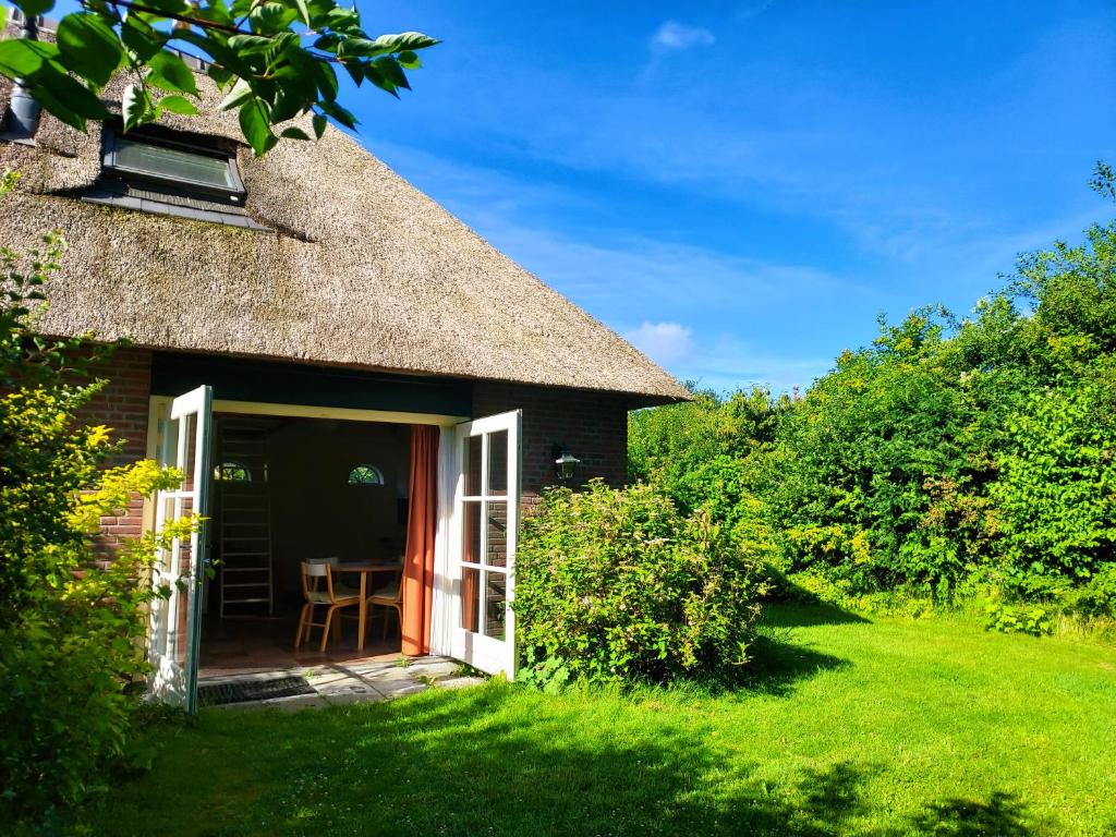 un cottage au toit de chaume avec un jardin de chaume dans l'établissement Uylkenshof safaritenten en natuurhuisjes, à Epe