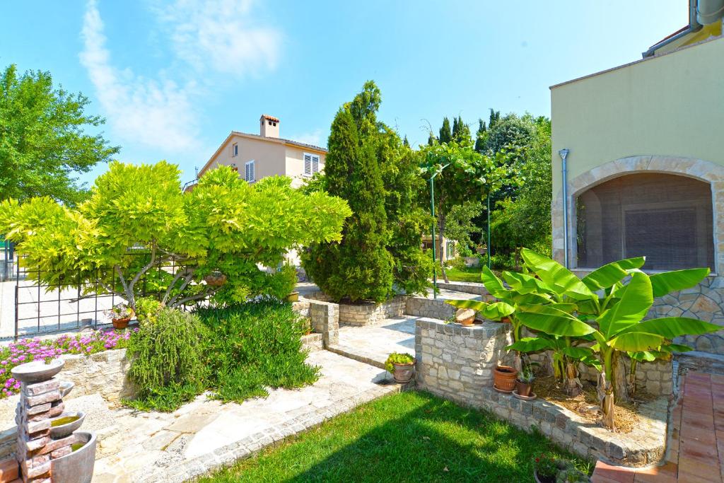 einen Garten mit Bäumen und Pflanzen vor einem Haus in der Unterkunft Apartment Damira 1017 in Fažana