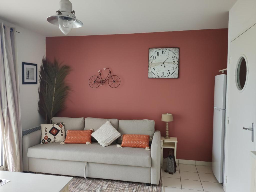 uma sala de estar com um sofá e um relógio na parede em Superbe appartement avec piscine sauna et petite vue mer em Plougonvelin