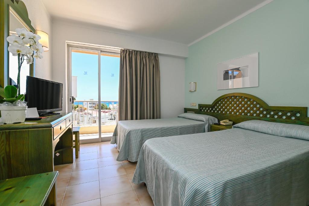 ein Hotelzimmer mit 2 Betten und einem TV in der Unterkunft HOTEL ALONDRA in Cala Ratjada