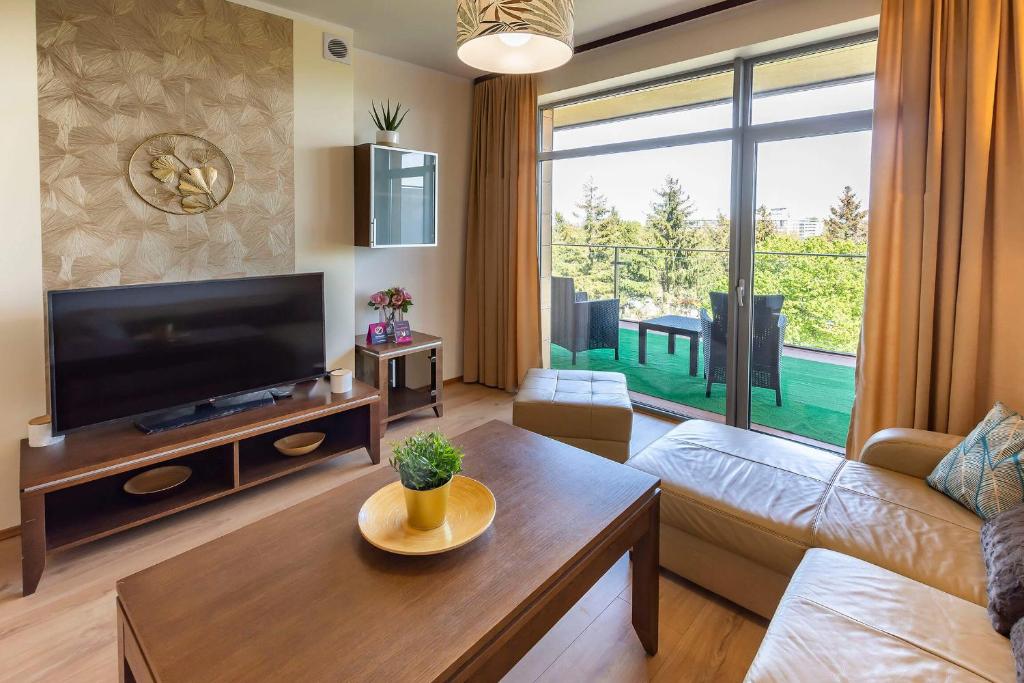 a living room with a couch and a tv at VacationClub - Diune Apartment 64 in Kołobrzeg