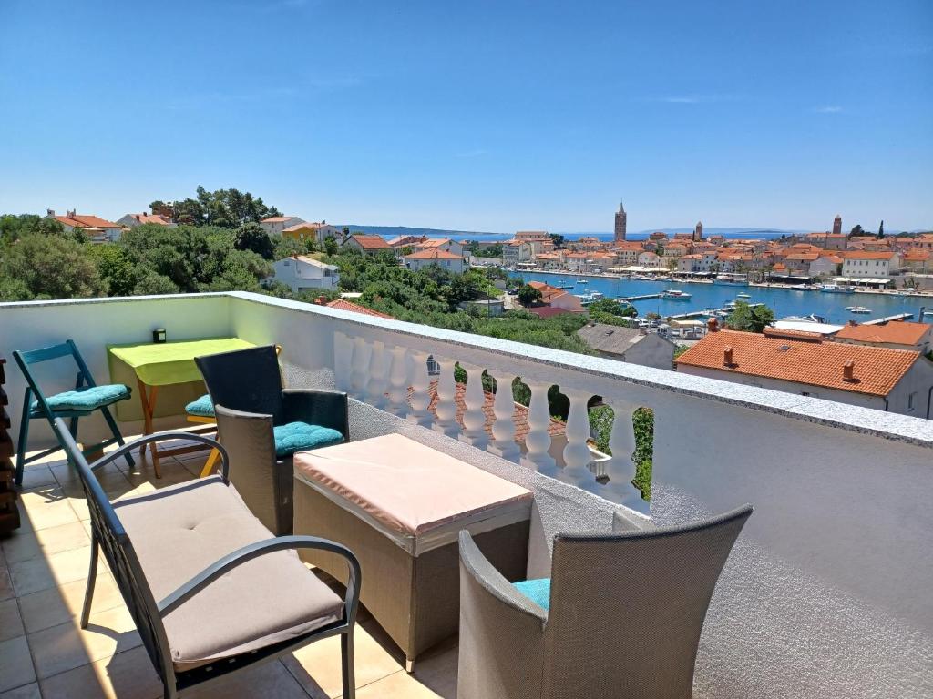 a balcony with chairs and tables and a view of the city at Apartments Ivić in Rab
