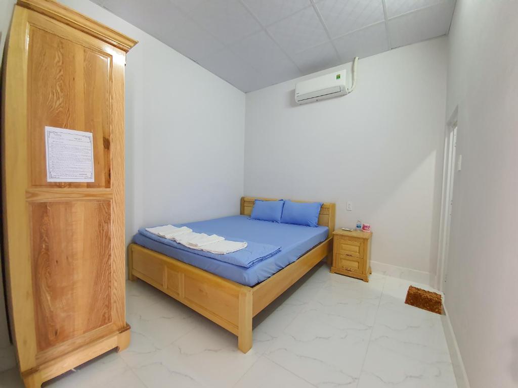 a small bedroom with a blue bed and a wooden cabinet at MƯỜI HOMESTAY in Con Dao